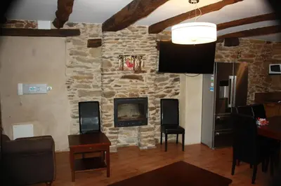 a living room with a stone wall and a tv at Alojamiento Luz de Hadas in Sampil