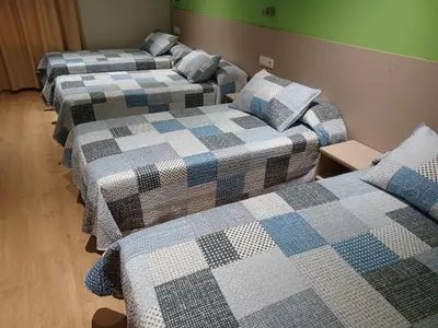 a row of three beds in a room at Hosteria de Gonzar in Gonzar