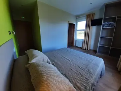 a bedroom with a bed with green walls and a window at Hosteria de Gonzar in Gonzar