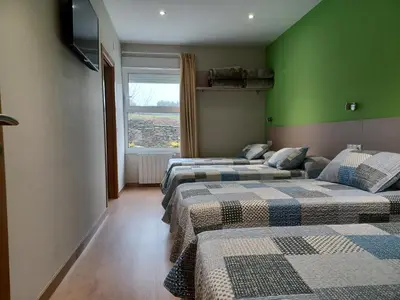 two beds in a room with green walls and a window at Hosteria de Gonzar in Gonzar