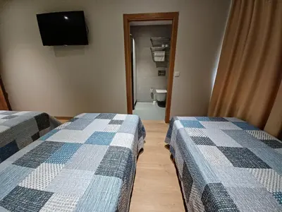 a room with two beds and a bathroom with a toilet at Hosteria de Gonzar in Gonzar