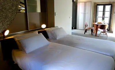a large white bed in a room with a table at Blanco Apartamentos Turísticos in Santiago de Compostela