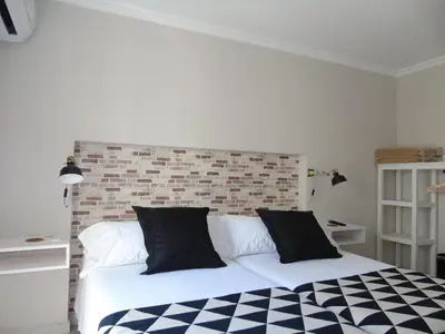 a bed with black and white sheets and a brick wall at Casa San Nicolás in Portomarin