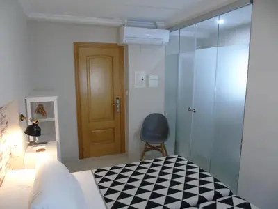 a bedroom with a bed and a chair and a door at Casa San Nicolás in Portomarin