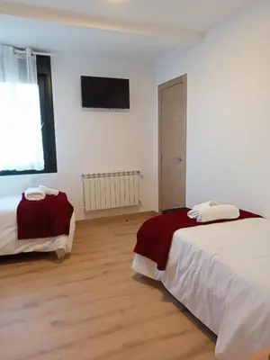 a white room with two beds and a television at Pension Xacobeo Lavacolla in Lavacolla