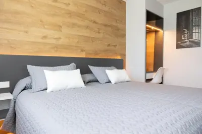 a bedroom with a large bed with a wooden wall at Hostal O'Cruceiro in O Pino
