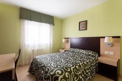 a bedroom with a bed and a desk and a window at Hotel Canaima Bruma 1,5 k Camino in O Mesón Do Vento