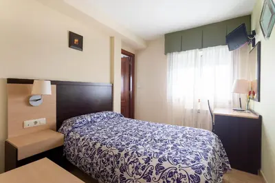 a bedroom with a blue and white bed and a window at Hotel Canaima Bruma 1,5 k Camino in O Mesón Do Vento
