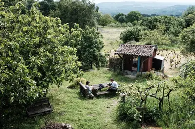 two people sitting on a bench in front of a cabin at Torre Tanquián Eco Finca - Ribeira Sacra in Pantón
