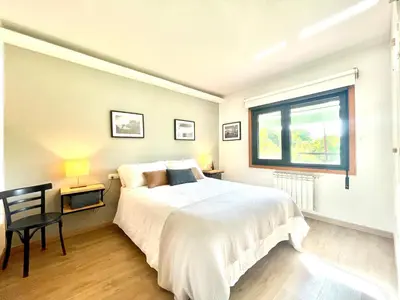 a white bedroom with a bed and a window at VILLA GUIMIL - GALICIA PLAYA in Villarmayor