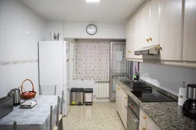a kitchen with a white refrigerator and a clock on the wall at Céntrico exterior amplio 110 m. in Santiago de Compostela