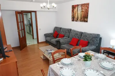 a living room with a couch and a table with red pillows at Céntrico exterior amplio 110 m. in Santiago de Compostela