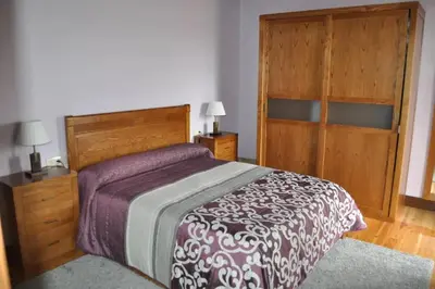 a bedroom with a bed and a wooden closet at Spacious House with Pool in Carballedo in Carballedo