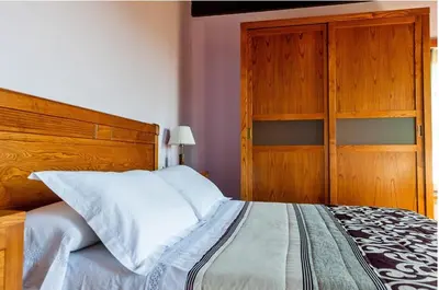 a bedroom with a large bed with a wooden headboard at Spacious House with Pool in Carballedo in Carballedo