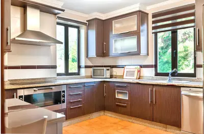 a large kitchen with wooden cabinets and windows at Spacious House with Pool in Carballedo in Carballedo