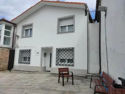 a white house with two benches in front of it at Casa Luis in Arzúa