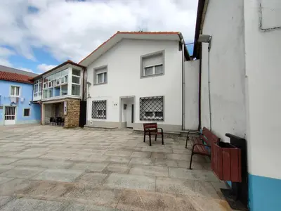 a white house with two benches in the courtyard at Casa Luis in Arzúa