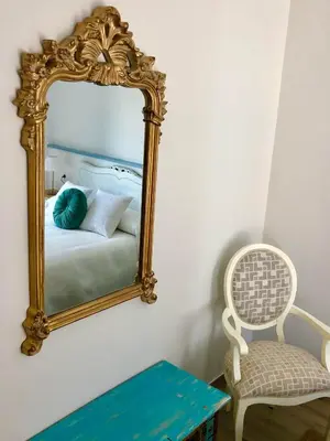 a mirror on a wall with a bed and a chair at Apartamentos Turísticos Casa Dina in Rinlo