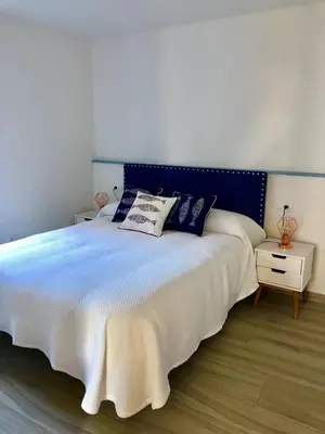 a bedroom with a large bed with a blue headboard at Apartamentos Turísticos Casa Dina in Rinlo