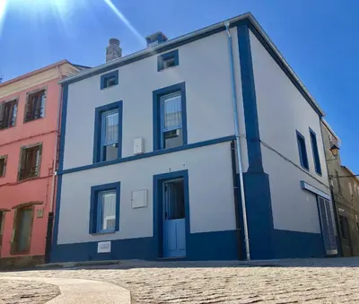 a blue and white building on a street at Apartamentos Turísticos Casa Dina in Rinlo