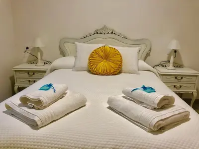a bedroom with a bed with towels and two night stands at Apartamentos Turísticos Casa Dina in Rinlo