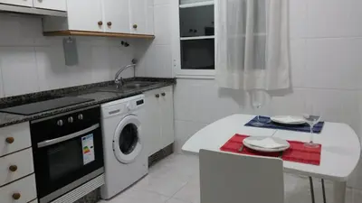 a kitchen with a washing machine and a table at Apartamento en el casco histórico in Santiago de Compostela