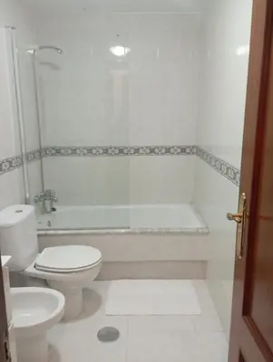 a white bathroom with a toilet and a bath tub at Apartamento en el casco histórico in Santiago de Compostela
