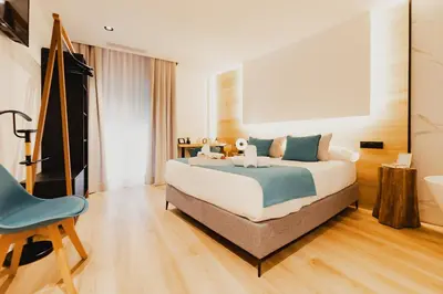 a bedroom with a large bed and a blue chair at HOTEL LOTUS in Caldas de Reis