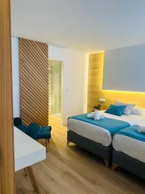 a bedroom with two beds and a chair in it at HOTEL LOTUS in Caldas de Reis