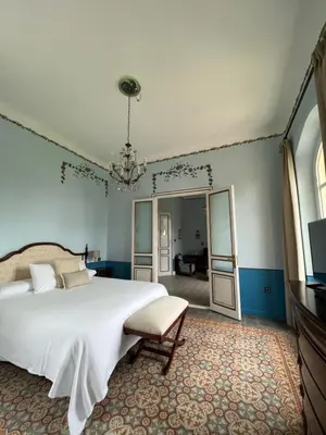 a bedroom with a large white bed and a chandelier at Hotel Palacete Peñalba in Castropol