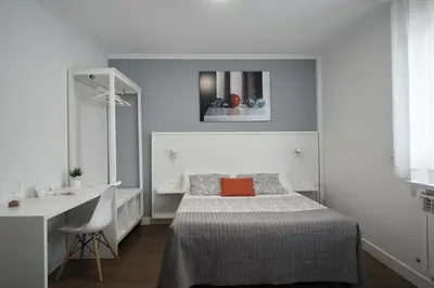 a white bedroom with a bed and a desk at Xabarin Rooms in Abadín