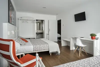 a white bedroom with a bed and a desk and a chair at Xabarin Rooms in Abadín