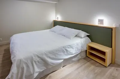 a bedroom with a large white bed and a night stand at APARTAMENTOS BARCELLA TAPIA in Tapia de Casariego