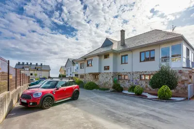 a red car parked in front of a house at APARTAMENTOS BARCELLA TAPIA in Tapia de Casariego