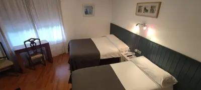 a hotel room with two beds and a table at Hostal Cruce in Villafranca del Bierzo