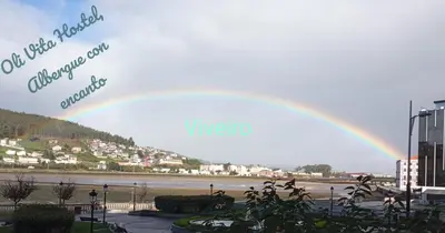 a rainbow in the sky over a city at Oli Vita Hostel ALBERGUE CON ENCANTO in Viveiro