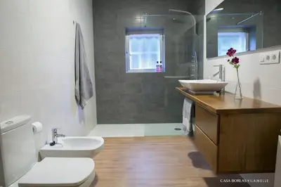 a bathroom with a toilet and two sinks and a shower at Casa Borlas in Vilamelle