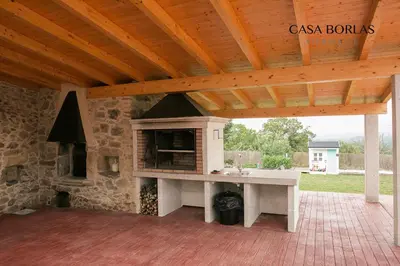 an outdoor kitchen with a stone fireplace on a patio at Casa Borlas in Vilamelle