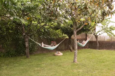 two people sitting in hammocks between two trees at Casa Borlas in Vilamelle