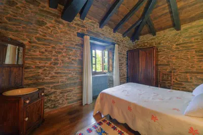 a bedroom with a bed and a brick wall at Casa Bouza in Becerreá
