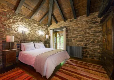 a bedroom with a bed and a stone wall at Casa Bouza in Becerreá