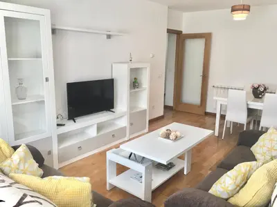 a living room with a tv and a table at Piso céntrico próximo a la playa in Burela de Cabo