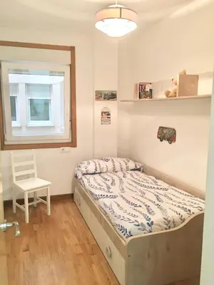 a bedroom with a bed and a chair in it at Piso céntrico próximo a la playa in Burela de Cabo