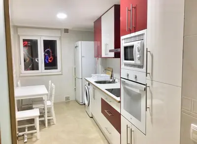 a kitchen with white appliances and a table and chairs at Piso céntrico próximo a la playa in Burela de Cabo