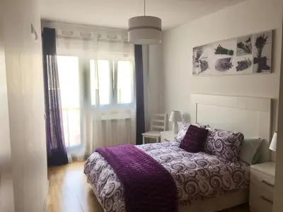 a bedroom with a purple bed and a window at Piso céntrico próximo a la playa in Burela de Cabo