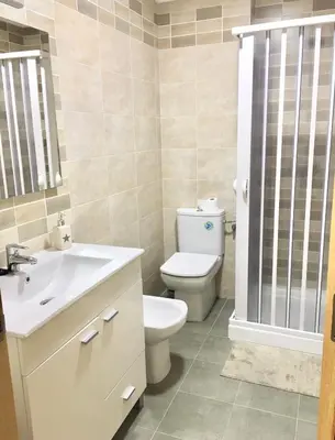a bathroom with a toilet and a sink and a shower at Piso céntrico próximo a la playa in Burela de Cabo