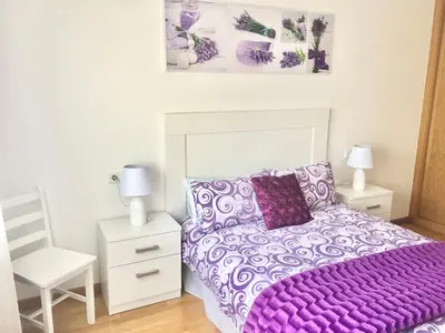 a bedroom with a purple bed and a white chair at Piso céntrico próximo a la playa in Burela de Cabo