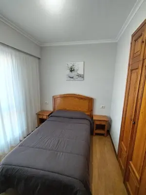 a bedroom with a bed and two wooden cabinets at HOSTAL CID in Ourense