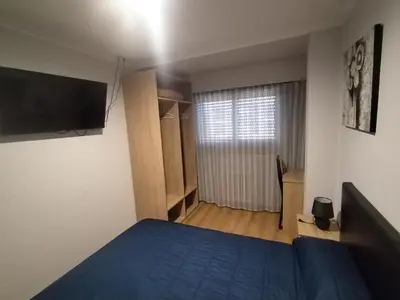 a bedroom with a blue bed and a television at HOSTAL CID in Ourense