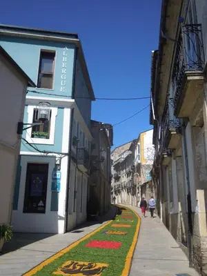 a narrow alley with people walking down the street at Albergue O Durmiñento in Sarria